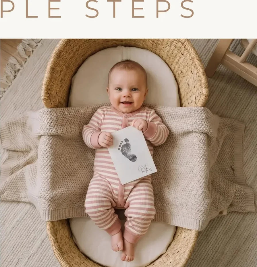 A baby holding a finished footprint milestone card