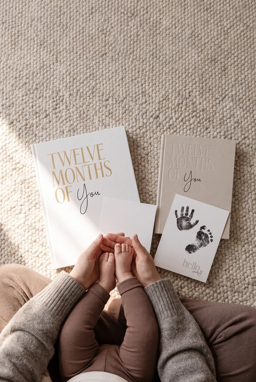 A parent holding a baby’s feet beside MinkTale keepsake albums and print cards